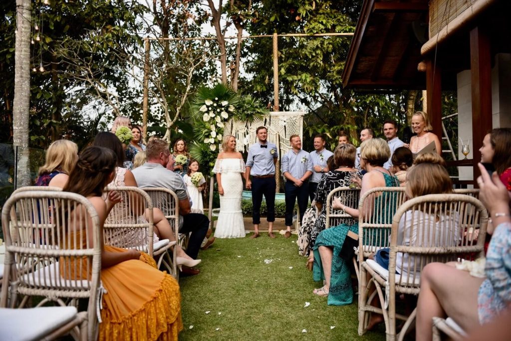 This is a picture of the ceremony. The couple are standing before a stunning macrame arbour.